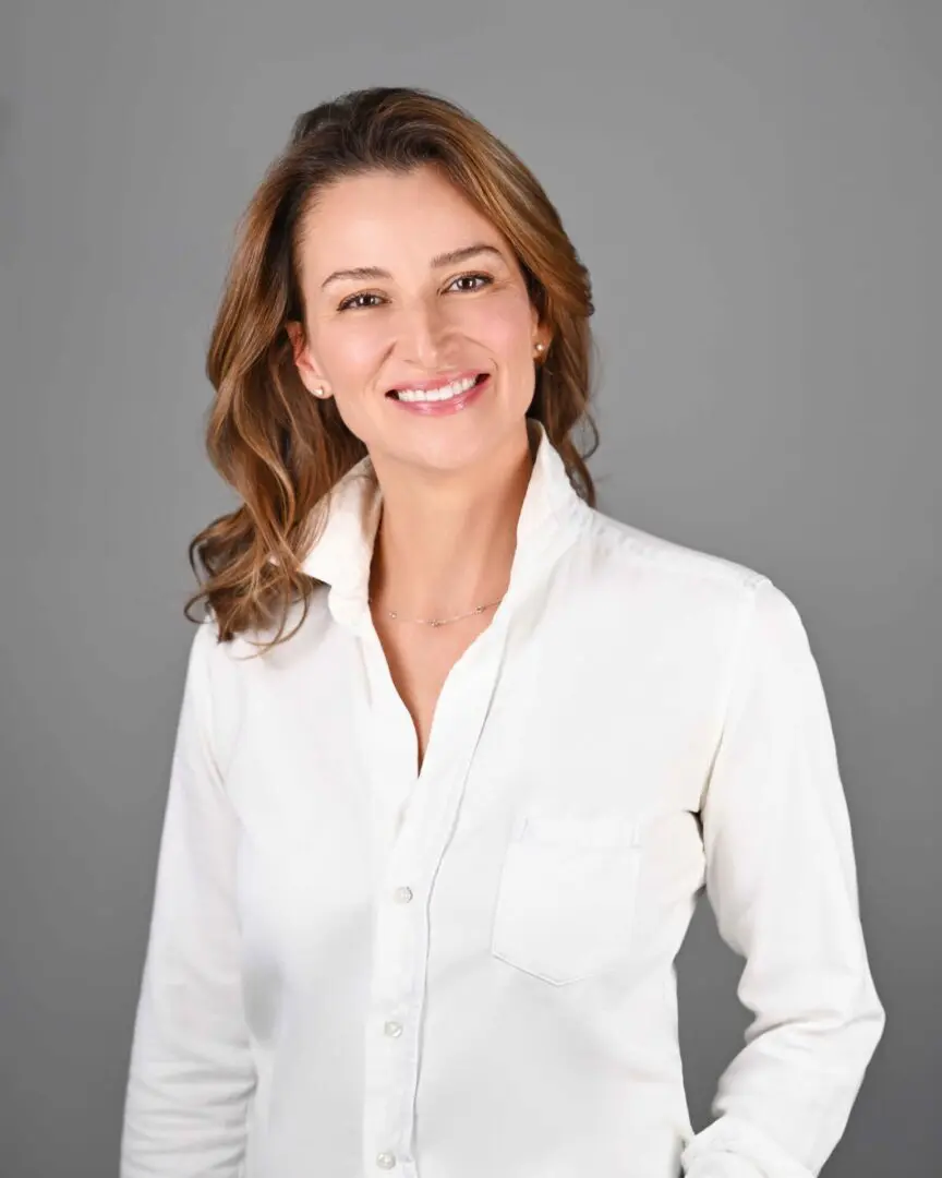 Smiling woman in white shirt against a plain background.